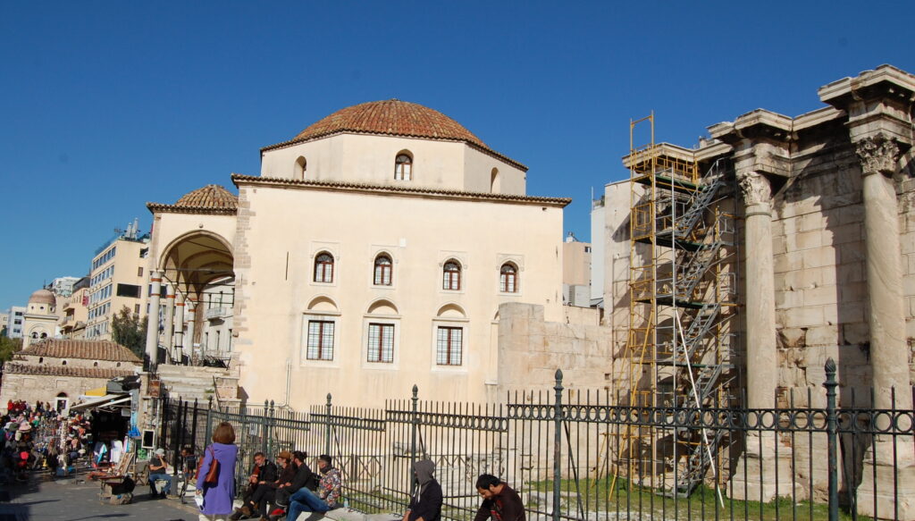 Colour photograph of classical building next to an Ottoman mosque in Athens.