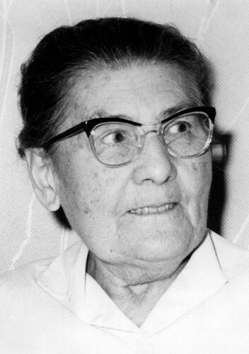 Black and white photograph of a white woman in glasses with dark hair.