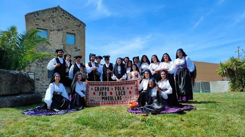 A colour photograph of a group of people dressed in folk costume holding a sign.